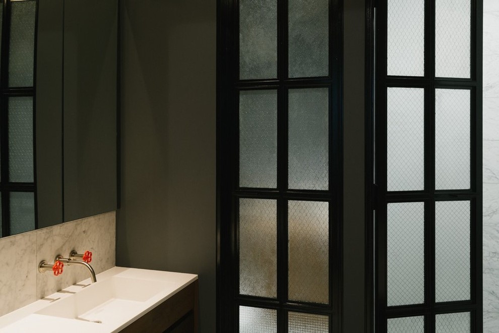 Inspiration pour un WC et toilettes design en bois foncé avec un carrelage beige, un carrelage blanc, un lavabo intégré et un plan de toilette en marbre.