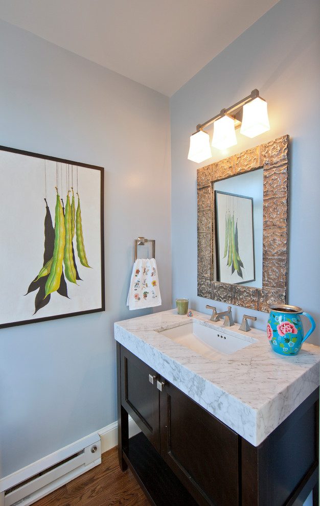 Cette image montre un WC et toilettes traditionnel en bois foncé de taille moyenne avec un lavabo encastré, un placard à porte shaker, un plan de toilette en marbre, WC à poser, un mur bleu et un sol en bois brun.