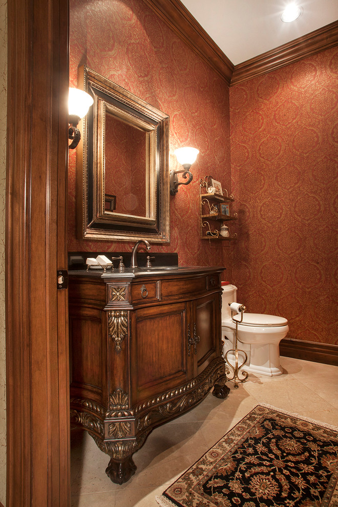Inredning av ett klassiskt toalett, med möbel-liknande, skåp i mörkt trä och röda väggar