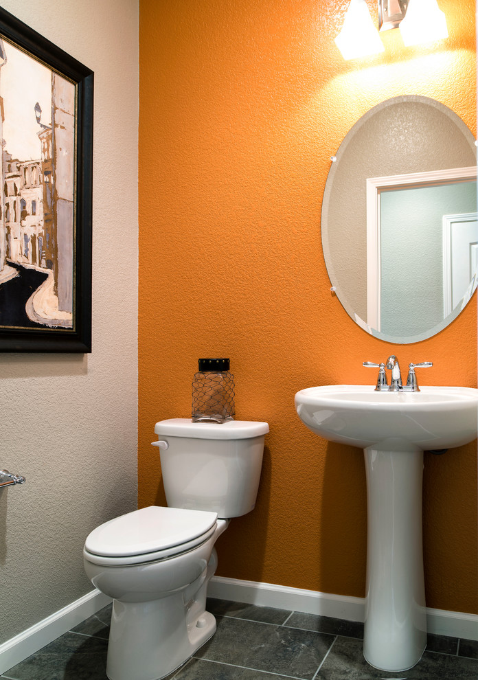 Idéer för mellanstora funkis toaletter, med en toalettstol med hel cisternkåpa, grå kakel, keramikplattor, orange väggar och ett piedestal handfat