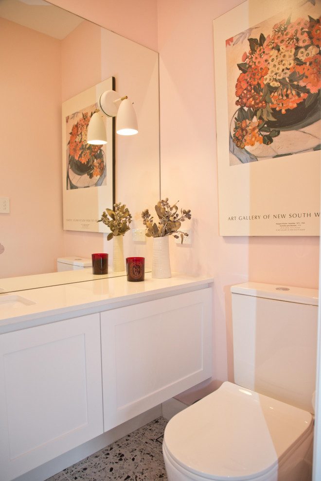 На фото: маленький туалет в современном стиле с фасадами в стиле шейкер, белыми фасадами, розовыми стенами, полом из галечной плитки и подвесной тумбой для на участке и в саду