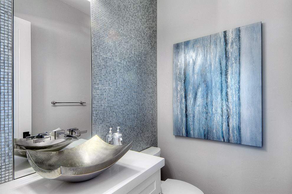 Свежая идея для дизайна: туалет среднего размера в стиле неоклассика (современная классика) с белыми фасадами, унитазом-моноблоком, синей плиткой, серыми стенами, настольной раковиной, столешницей из искусственного кварца и стеклянной плиткой - отличное фото интерьера