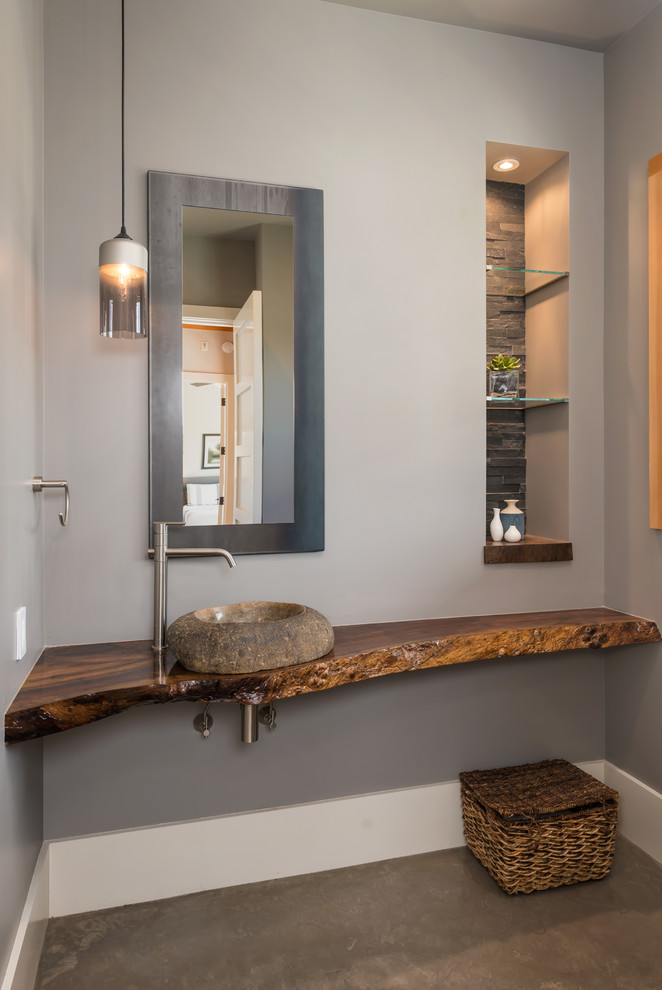 Immagine di un bagno di servizio stile rurale di medie dimensioni con lavabo a bacinella, top in legno, pareti grigie, pavimento in cemento e top marrone