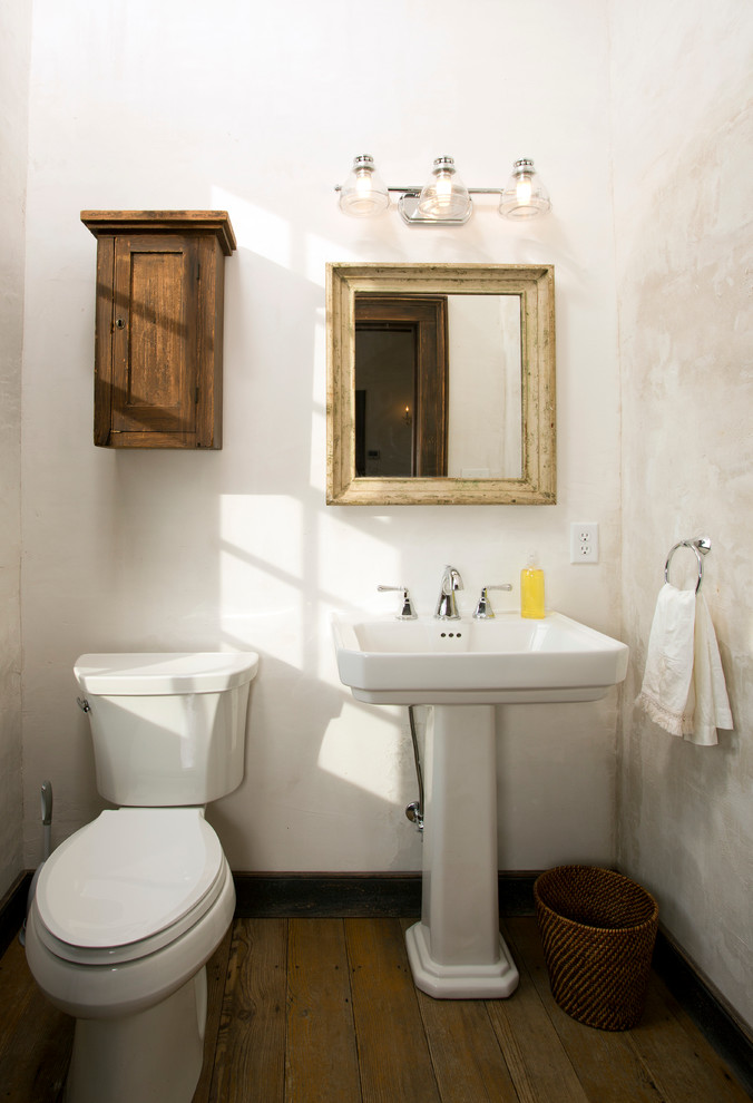 Ispirazione per un piccolo bagno di servizio country con WC a due pezzi, pareti bianche, pavimento in legno massello medio e lavabo a colonna