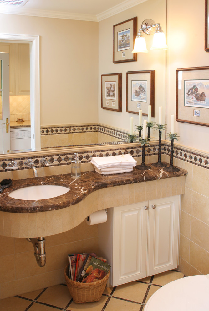 Foto di un bagno di servizio classico di medie dimensioni con lavabo sottopiano, ante con bugna sagomata, top in marmo, ante bianche, pareti beige e top marrone