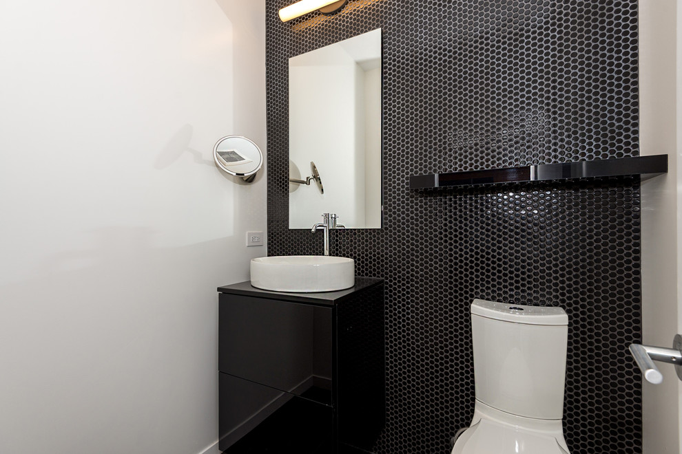 Inspiration for a small contemporary cloakroom in Ottawa with flat-panel cabinets, black cabinets, a one-piece toilet, black tiles, mosaic tiles, white walls and a vessel sink.