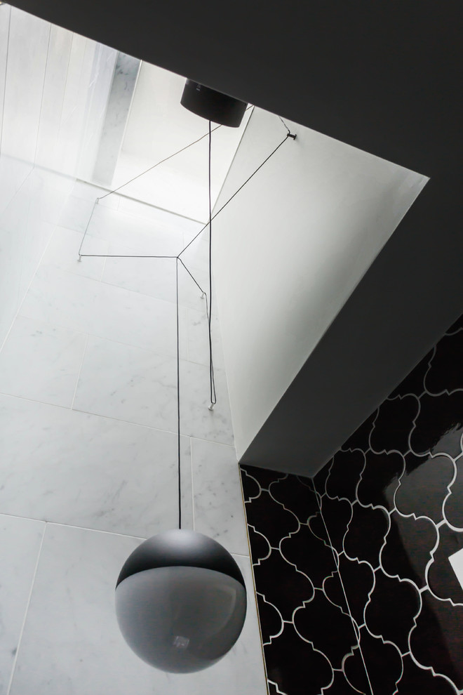 ニューヨークにある高級な小さなコンテンポラリースタイルのおしゃれなトイレ・洗面所 (セラミックタイル、モノトーンのタイル、黒い壁、大理石の床、壁付け型シンク、黒い床) の写真