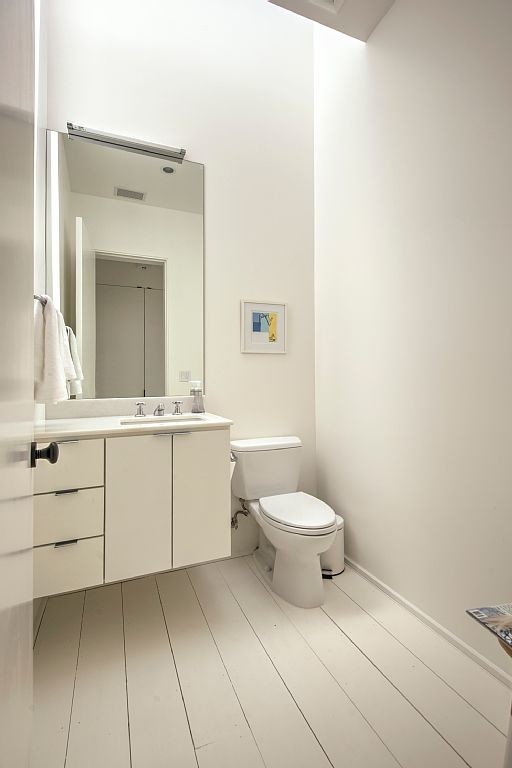 Inspiration for a mid-sized country white tile painted wood floor powder room remodel in San Francisco with an undermount sink, white cabinets, solid surface countertops, a two-piece toilet and white walls