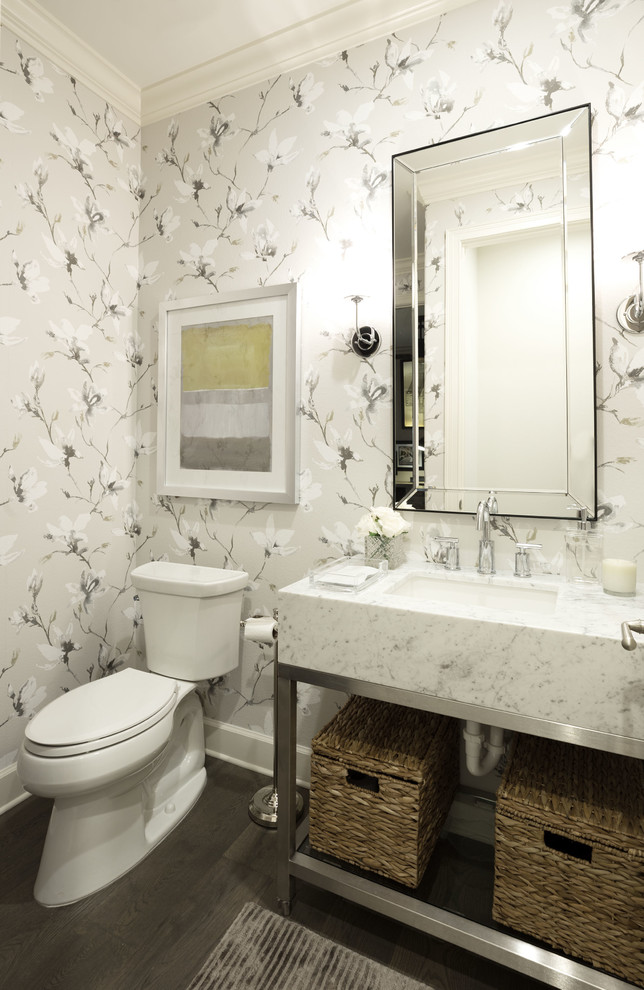 Klassisk inredning av ett mellanstort vit vitt toalett, med öppna hyllor, en toalettstol med separat cisternkåpa, grå väggar, ett undermonterad handfat, brunt golv, mörkt trägolv och marmorbänkskiva