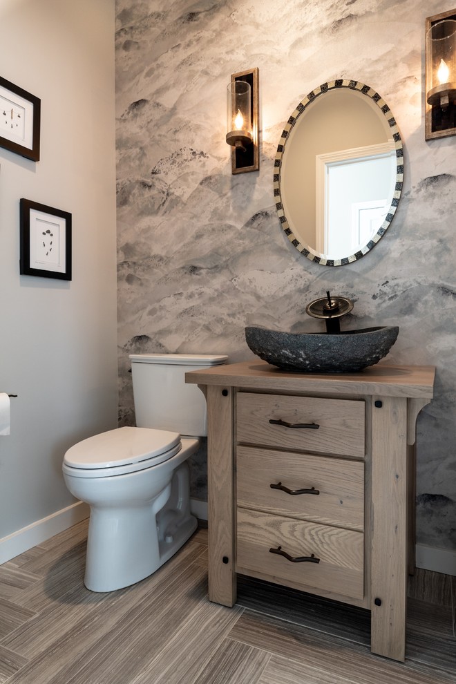 Aménagement d'un petit WC et toilettes classique en bois brun avec un placard à porte plane, WC séparés, un mur gris, un sol en carrelage de porcelaine, une vasque, un plan de toilette en bois, un sol gris et un plan de toilette beige.