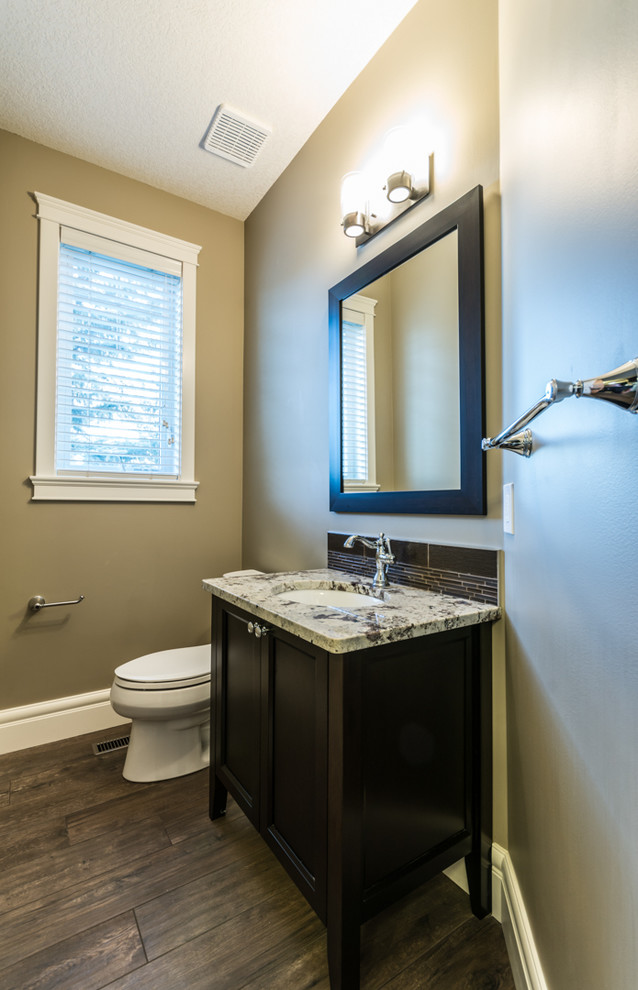 Example of a small arts and crafts brown tile and glass tile porcelain tile powder room design in Edmonton with an undermount sink, shaker cabinets, dark wood cabinets, granite countertops, a two-piece toilet and beige walls
