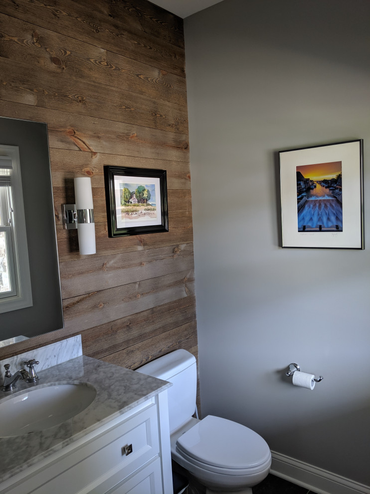 Immagine di un bagno di servizio tradizionale con ante con riquadro incassato, ante gialle, WC a due pezzi, piastrelle marroni, pareti grigie, lavabo sottopiano, top in marmo e top bianco