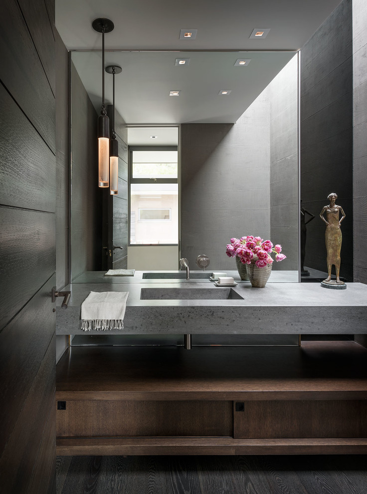 Mid-century modern dark wood floor and brown floor powder room photo in Orange County with flat-panel cabinets, dark wood cabinets, gray walls, an integrated sink and gray countertops