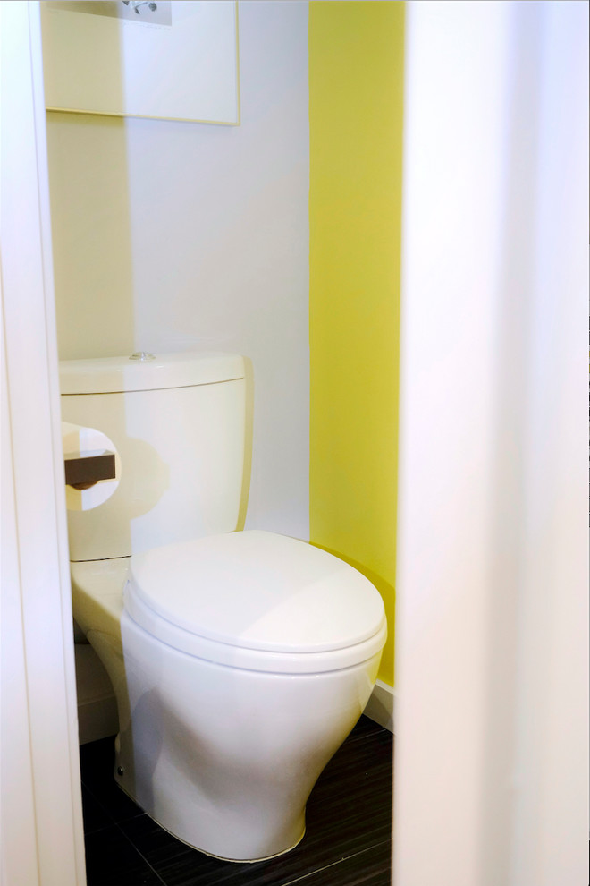 This is an example of a small contemporary cloakroom in San Francisco with flat-panel cabinets, light wood cabinets, a one-piece toilet, yellow tiles, yellow walls, ceramic flooring, a vessel sink, granite worktops, black floors and black worktops.