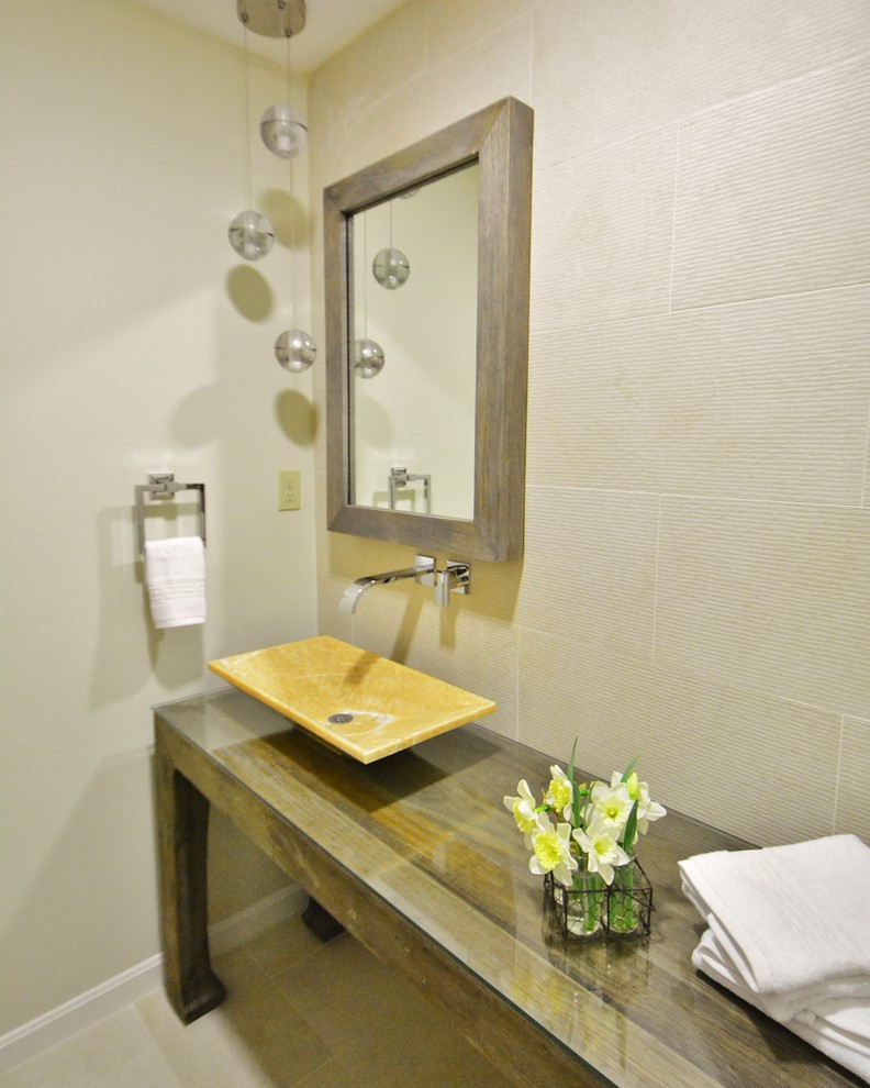 Immagine di un bagno di servizio minimal con lavabo a bacinella, consolle stile comò, ante in legno scuro, top in vetro, piastrelle beige e piastrelle in gres porcellanato