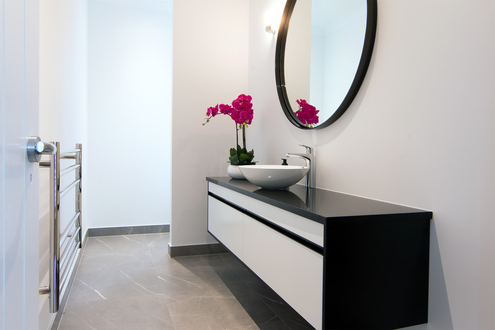 Пример оригинального дизайна: туалет среднего размера в современном стиле с белыми фасадами, унитазом-моноблоком, полом из керамогранита, столешницей из искусственного кварца, серым полом, черной столешницей и подвесной тумбой