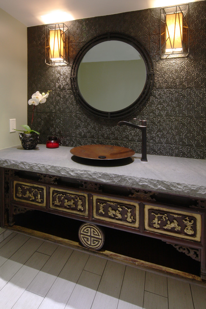 Kleine Asiatische Gästetoilette mit verzierten Schränken, dunklen Holzschränken, braunen Fliesen, Porzellan-Bodenfliesen, Aufsatzwaschbecken, Metallfliesen und schwarzer Wandfarbe in Los Angeles