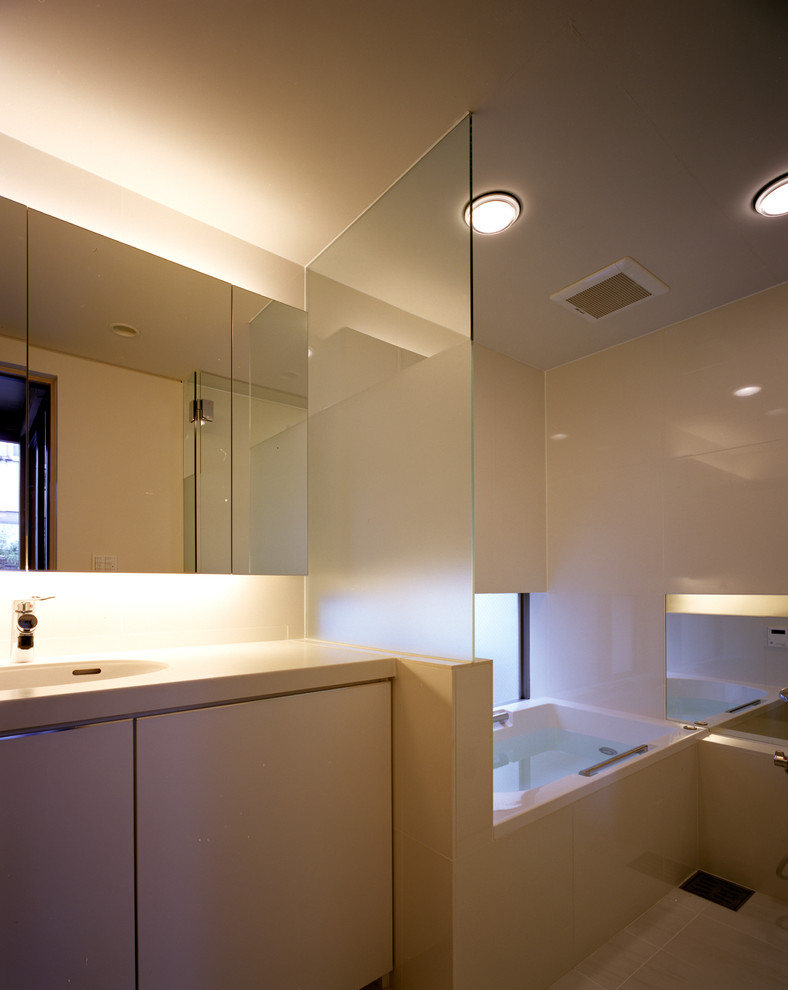 Exempel på ett litet skandinaviskt vit vitt toalett, med vita skåp, vit kakel, keramikplattor, vita väggar, klinkergolv i keramik, ett undermonterad handfat, bänkskiva i akrylsten, vitt golv och luckor med profilerade fronter