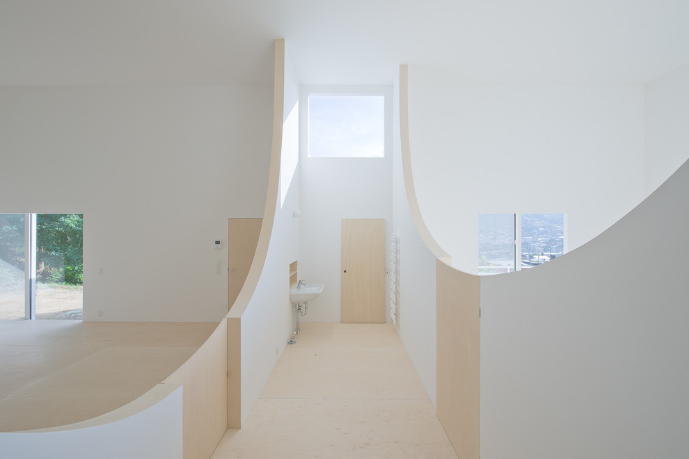 Ejemplo de aseo contemporáneo con paredes blancas, suelo de madera clara y lavabo suspendido