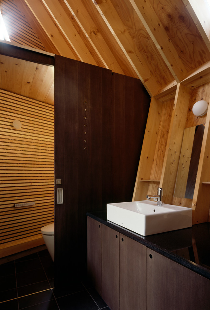 Exemple d'un WC et toilettes asiatique avec un placard à porte plane, des portes de placard marrons, WC à poser, une vasque et un mur marron.