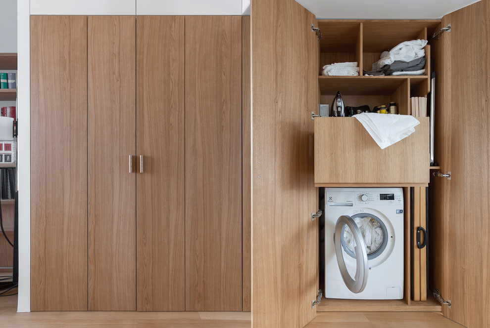 Imagen de armario lavadero contemporáneo pequeño con suelo de madera en tonos medios, puertas de armario de madera oscura, suelo marrón y lavadora y secadora integrada