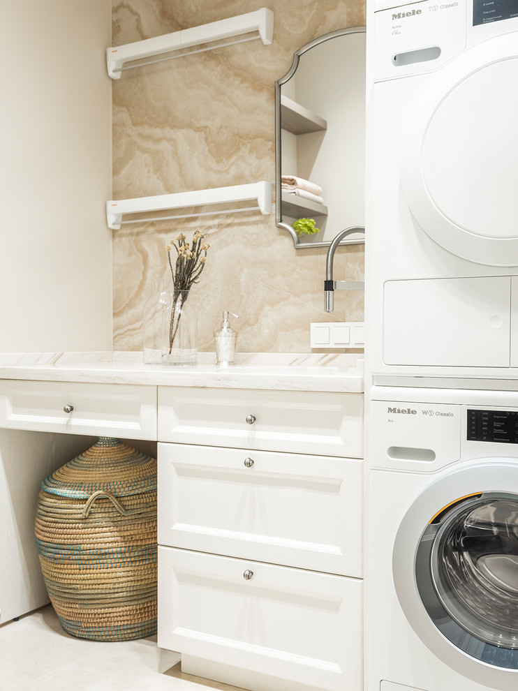 Ejemplo de lavadero tradicional renovado con armarios con paneles empotrados, puertas de armario blancas, paredes blancas y lavadora y secadora apiladas