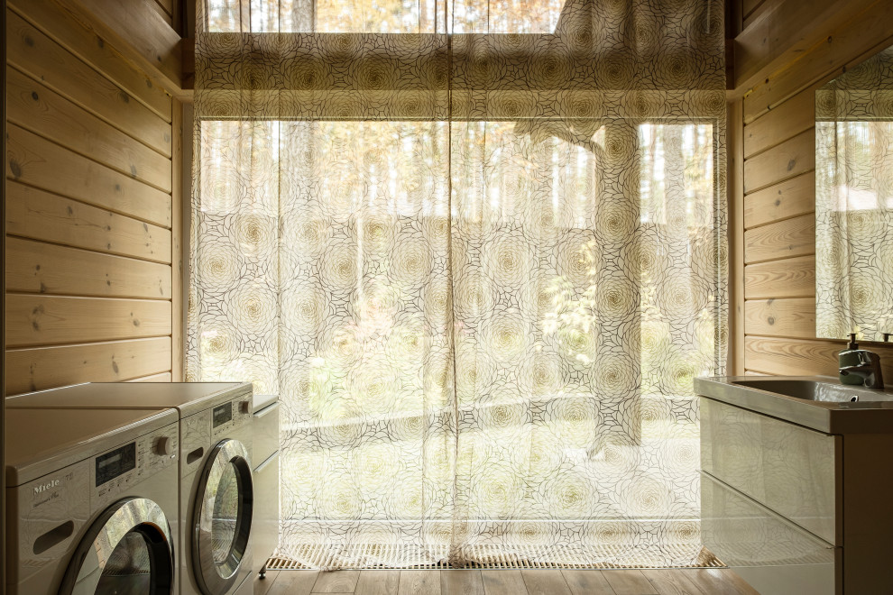Esempio di una sala lavanderia di medie dimensioni con lavello a vasca singola, ante bianche, lavatrice e asciugatrice affiancate e pareti in legno