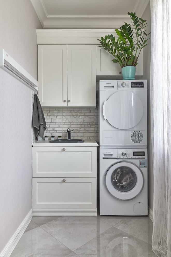 Foto di una sala lavanderia tradizionale con lavello da incasso, ante in stile shaker, ante bianche, pareti grigie, lavatrice e asciugatrice a colonna, pavimento grigio e top bianco