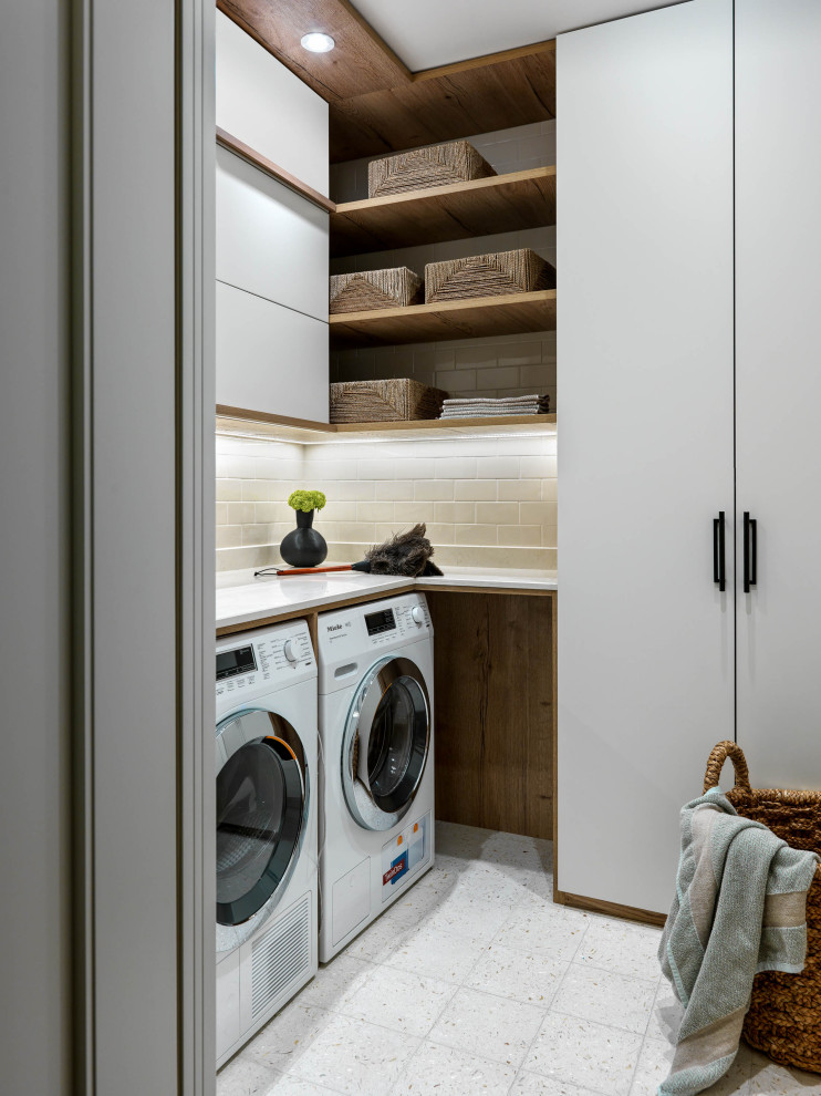 Diseño de cuarto de lavado en U contemporáneo pequeño con armarios con paneles lisos, puertas de armario blancas, encimera de mármol, lavadora y secadora juntas, suelo blanco y encimeras blancas
