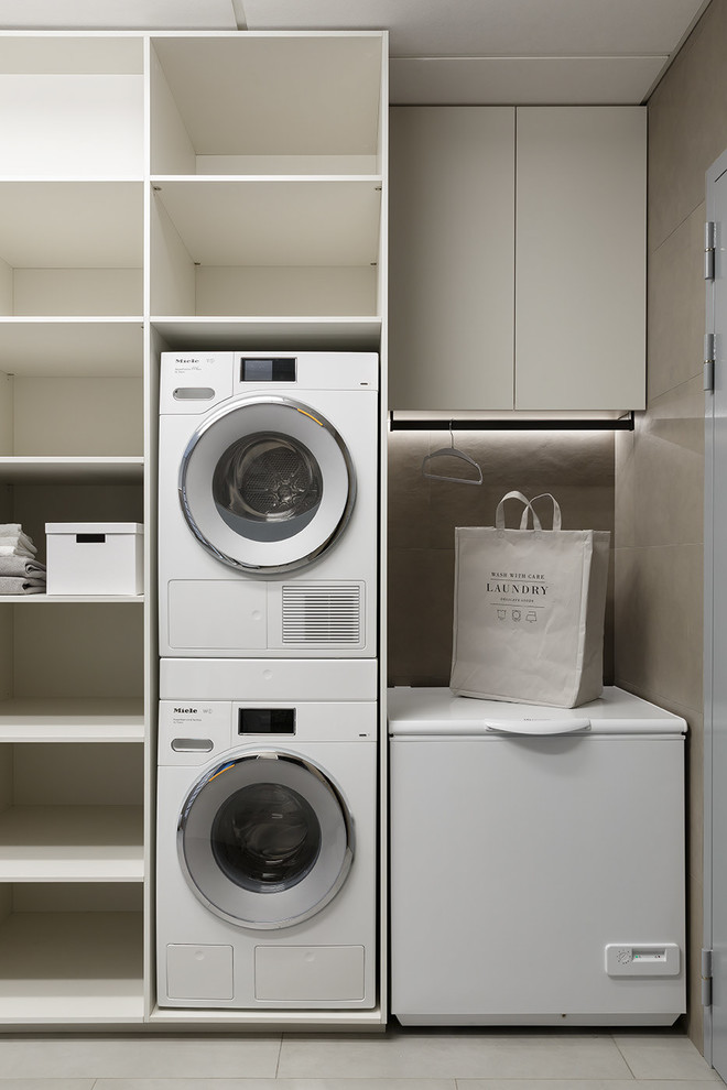 Modelo de lavadero contemporáneo con puertas de armario grises, paredes beige, suelo de baldosas de porcelana y suelo beige
