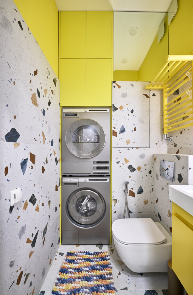 Design ideas for a small contemporary single-wall utility room in Moscow with a single-bowl sink, flat-panel cabinets, yellow cabinets, composite countertops, white splashback, porcelain splashback, multi-coloured walls, porcelain flooring, a stacked washer and dryer, multi-coloured floors and white worktops.