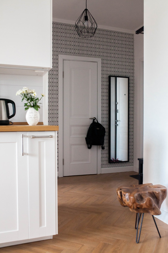 Imagen de puerta principal escandinava de tamaño medio con paredes grises, suelo de madera en tonos medios, puerta simple, puerta blanca y suelo marrón
