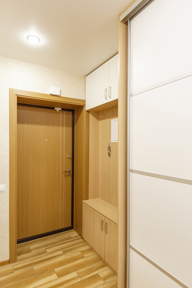 他の地域にある低価格の小さなコンテンポラリースタイルのおしゃれな玄関ドア (ベージュの壁、磁器タイルの床、木目調のドア、茶色い床) の写真
