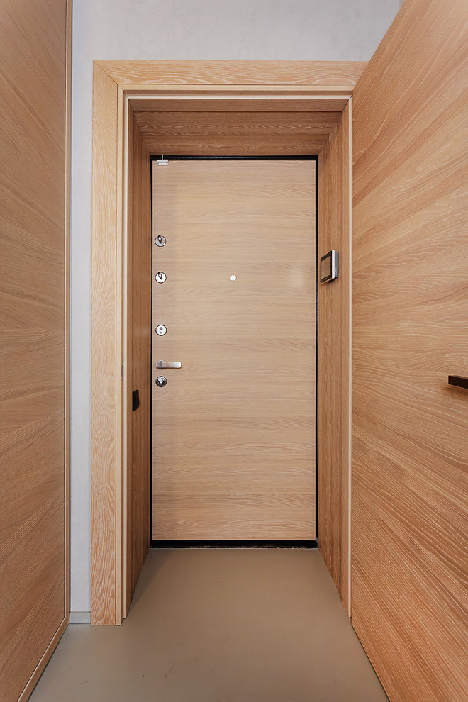 Immagine di un piccolo ingresso o corridoio design con pareti grigie, una porta singola, una porta in legno chiaro e pavimento grigio