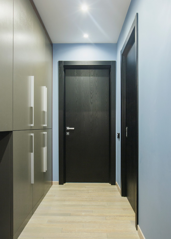 Foto på en liten industriell hall, med blå väggar, laminatgolv, en enkeldörr, en svart dörr och beiget golv