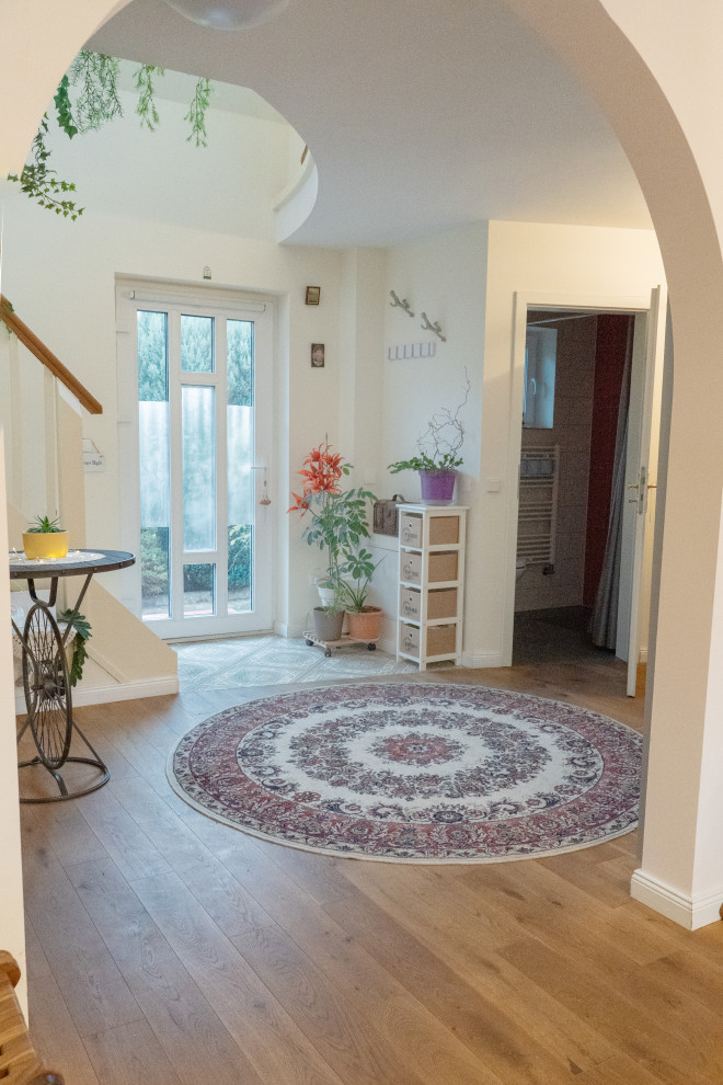 Kleiner Eingang mit Vestibül, beiger Wandfarbe, gebeiztem Holzboden, Einzeltür, weißer Haustür und beigem Boden
