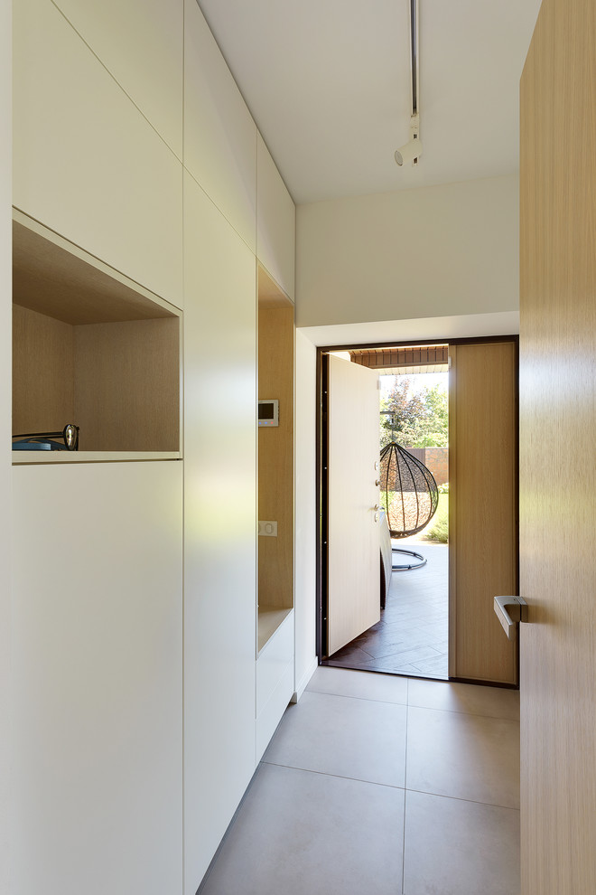 Foto di un piccolo ingresso con vestibolo minimal con pareti bianche, pavimento in gres porcellanato, una porta a due ante e una porta in legno chiaro
