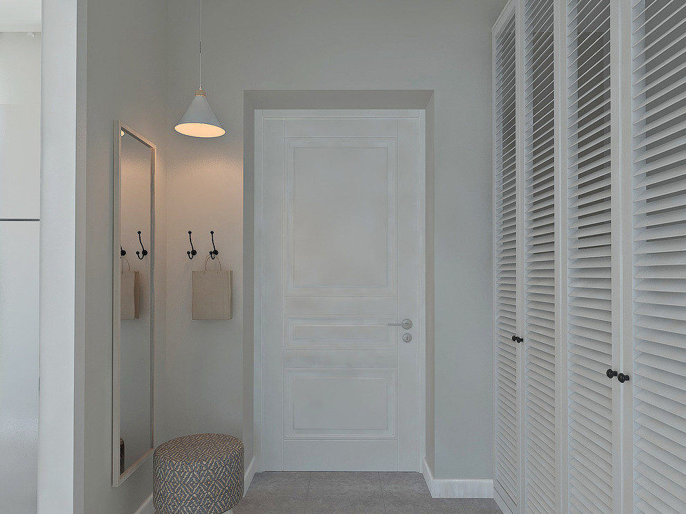 Стильный дизайн: маленькая прихожая в скандинавском стиле с серыми стенами, полом из керамогранита, одностворчатой входной дверью, белой входной дверью и серым полом для на участке и в саду - последний тренд