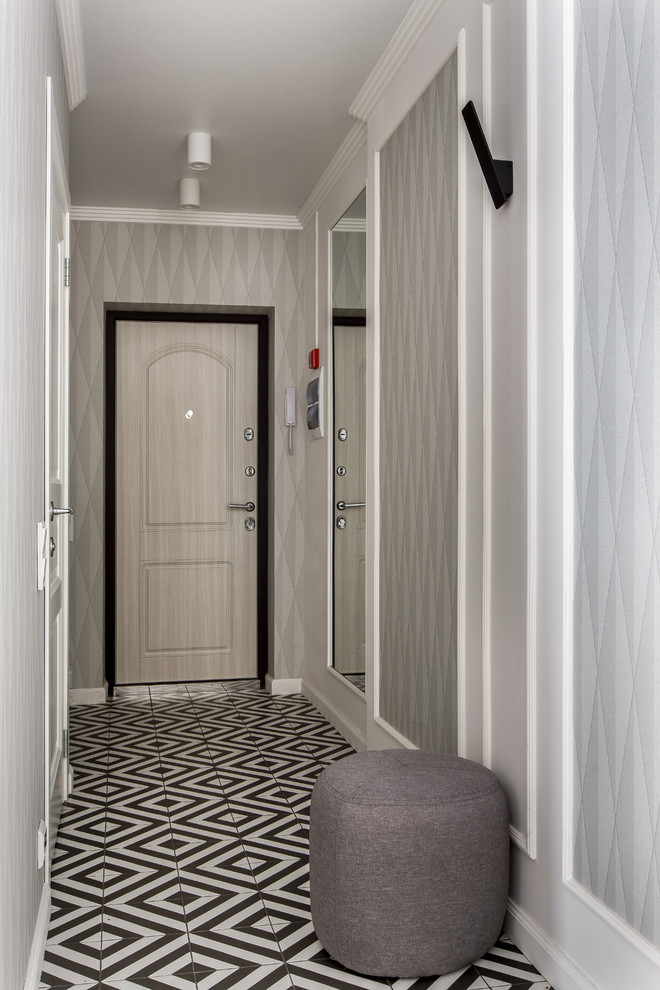 Aménagement d'une porte d'entrée classique avec un mur gris, une porte simple, une porte en bois clair et un sol multicolore.