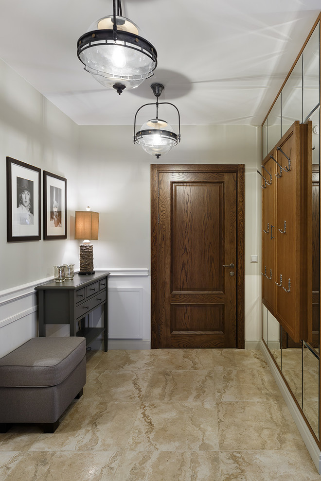 На фото: входная дверь: освещение в стиле неоклассика (современная классика) с белыми стенами, одностворчатой входной дверью, входной дверью из дерева среднего тона и бежевым полом