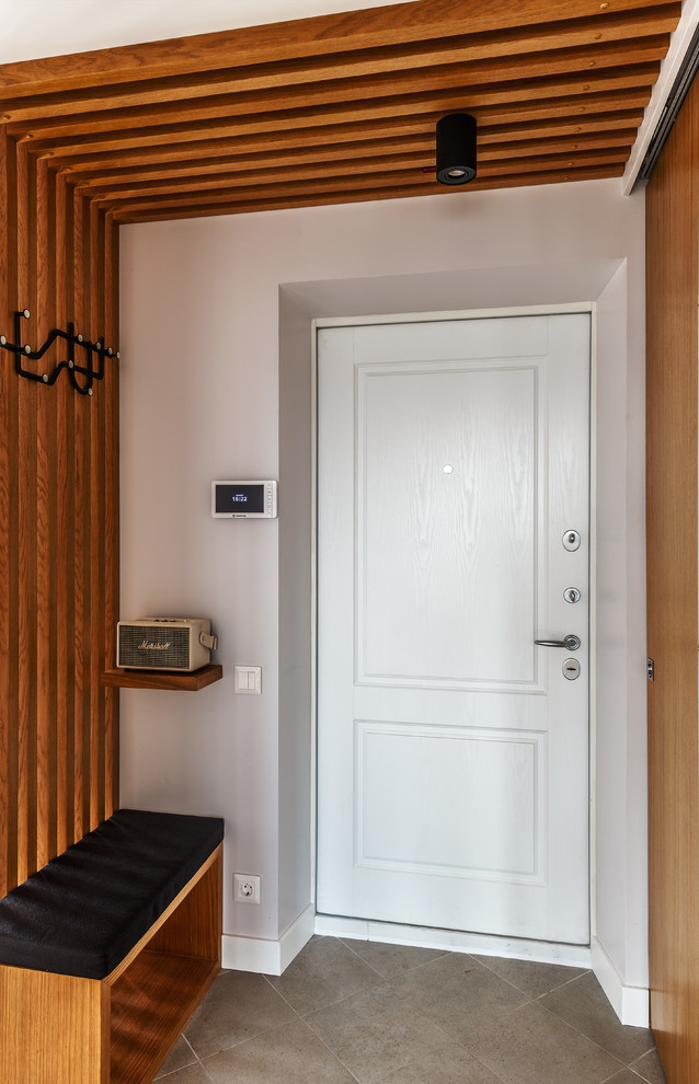 Inredning av en modern ingång och ytterdörr, med vita väggar, en enkeldörr, en vit dörr och grått golv