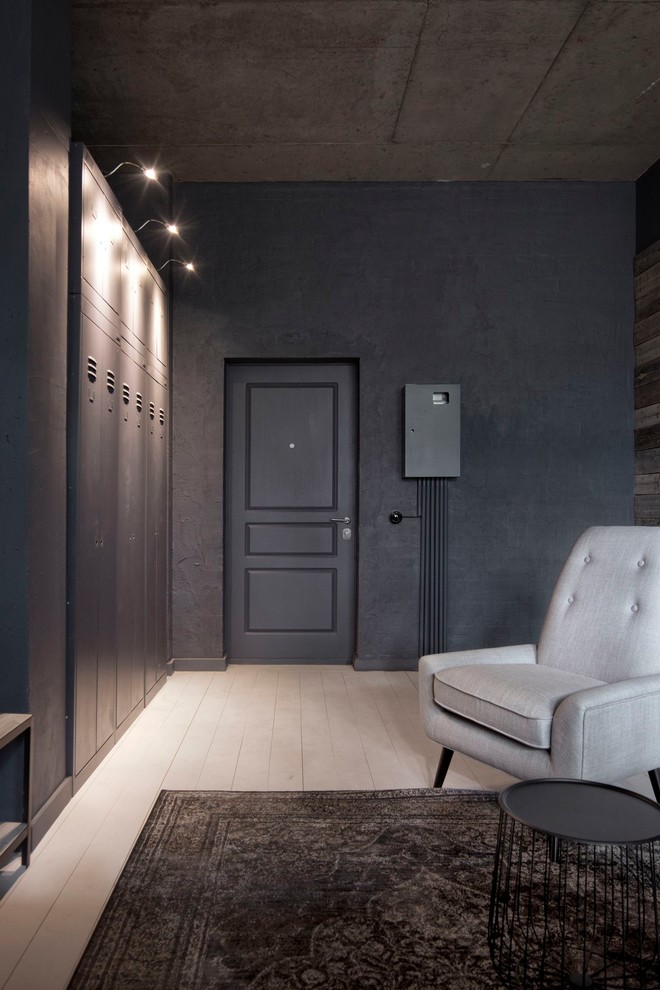 Cette image montre une petite porte d'entrée urbaine avec un mur gris, parquet peint, une porte simple, un sol blanc et une porte noire.