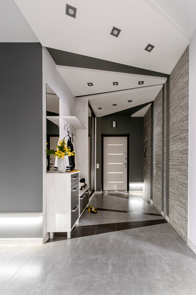 Diseño de hall contemporáneo grande con paredes grises, suelo de baldosas de porcelana, puerta simple, puerta de madera clara y suelo gris
