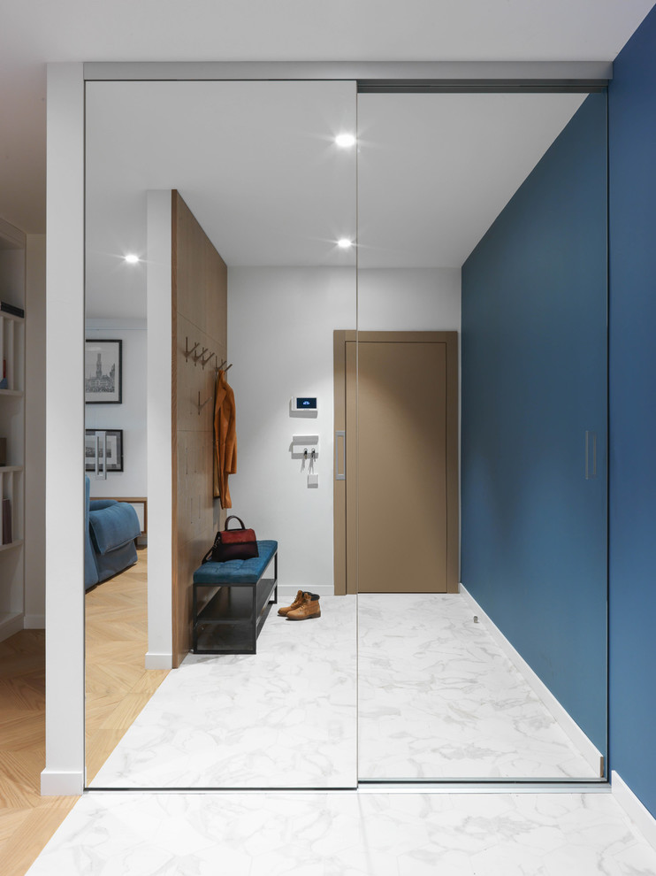 Пример оригинального дизайна: прихожая в современном стиле с синими стенами, одностворчатой входной дверью и белым полом