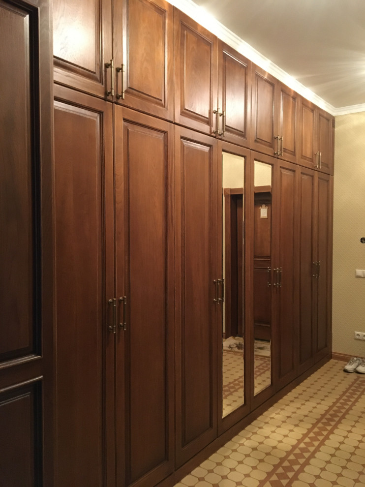 Modelo de hall clásico, grande, con paredes beige, suelo de baldosas de cerámica, puerta simple, puerta de madera oscura, suelo beige y papel pintado