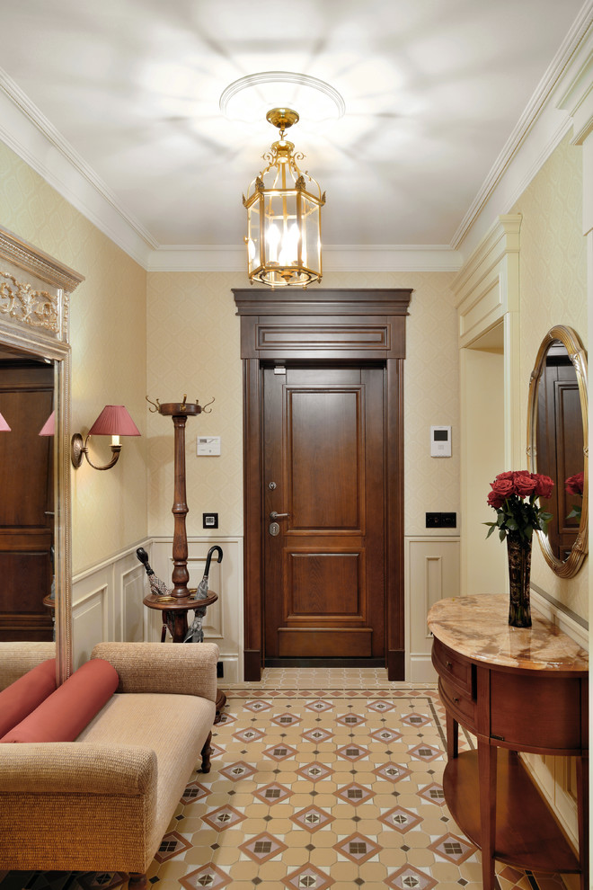 На фото: прихожая в классическом стиле с бежевыми стенами, одностворчатой входной дверью и входной дверью из дерева среднего тона с