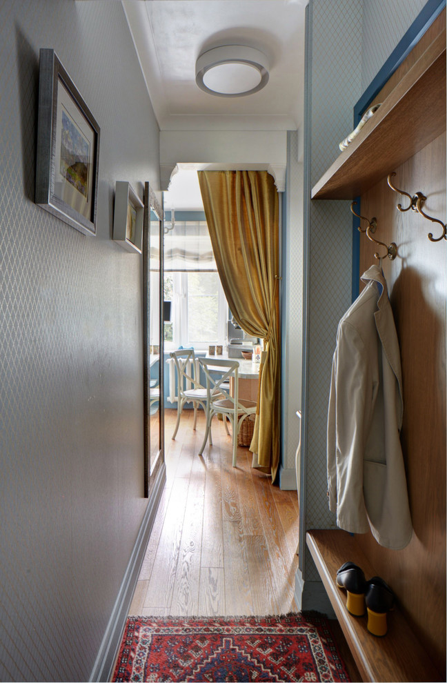 Inspiration pour une petite entrée avec un couloir, un mur bleu et un sol en bois brun.
