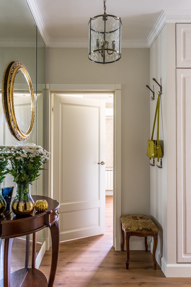 Imagen de puerta principal clásica pequeña con paredes beige, suelo de madera en tonos medios, puerta simple y puerta blanca
