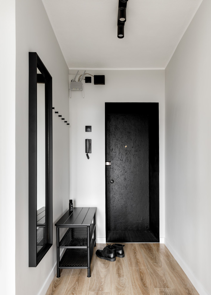 На фото: маленькая входная дверь в современном стиле с серыми стенами, полом из ламината, одностворчатой входной дверью, черной входной дверью и коричневым полом для на участке и в саду с