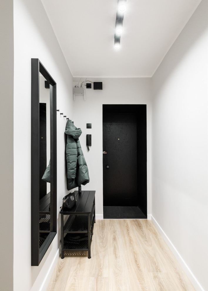 Modern inredning av en liten ingång och ytterdörr, med grå väggar, laminatgolv, en enkeldörr, en svart dörr och brunt golv